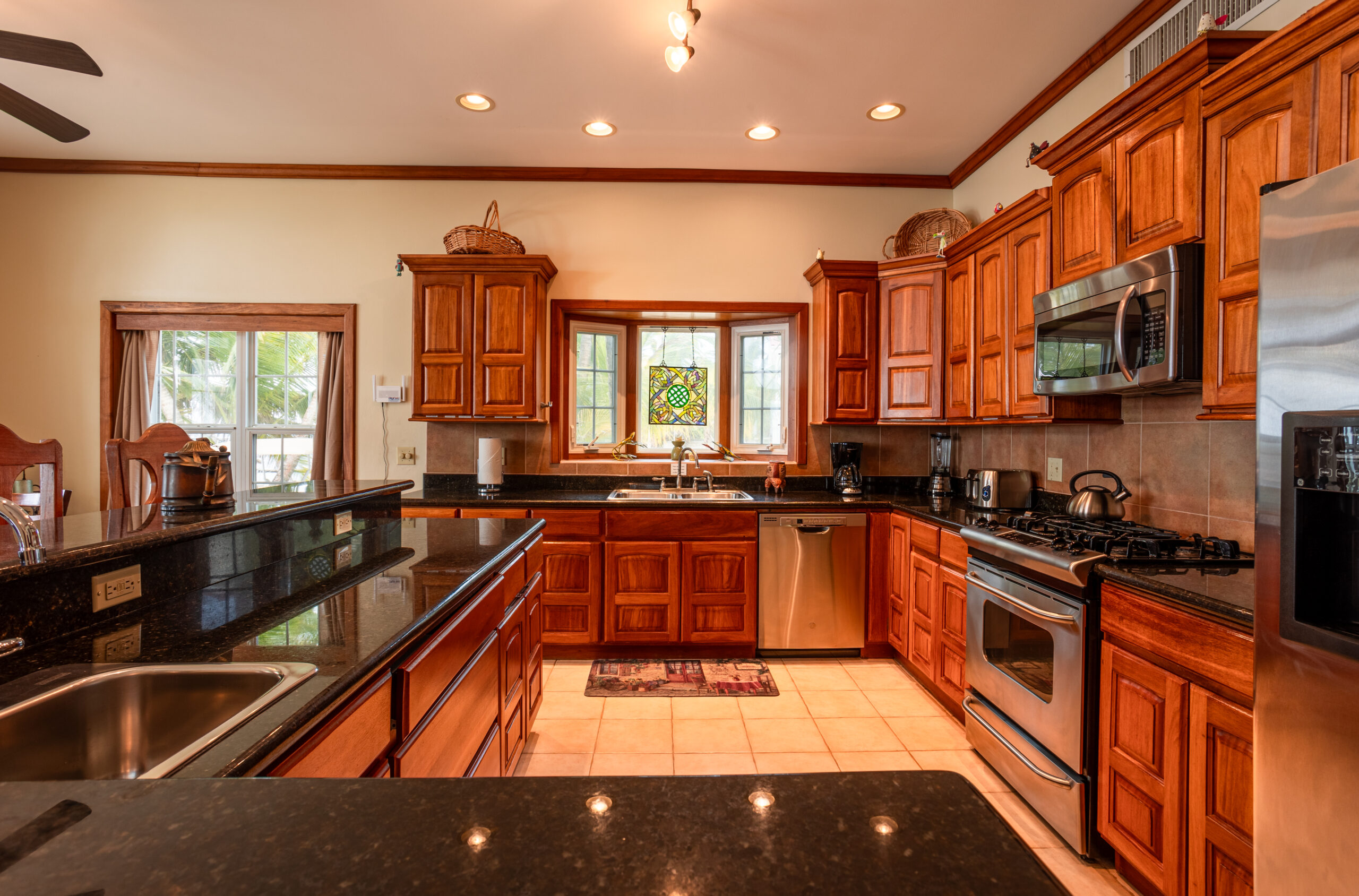 Fully equipped, modern kitchen with sleek appliances, granite countertops, and tropical accents, providing a convenient and functional space for cooking and entertaining.